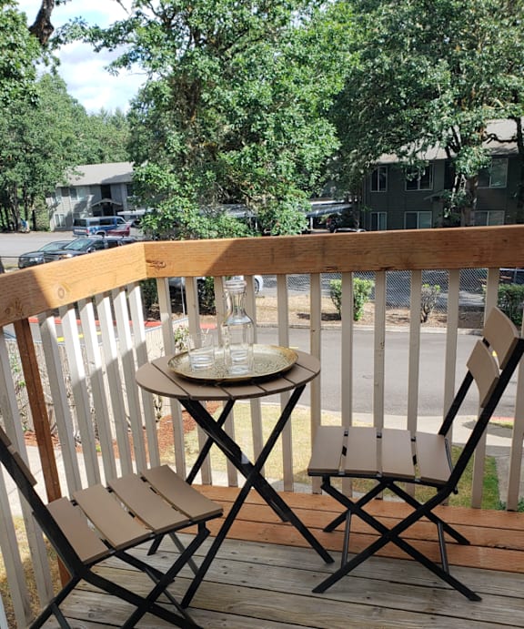 A table with two chairs on a wooden deck.