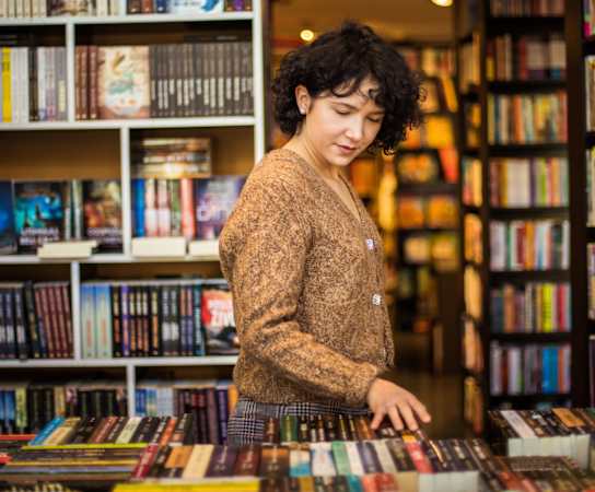 a woman looking at books in a bookstore at Maven on Broadway, Rochester, 55904