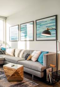A living room with a grey couch, a wooden coffee table, and a large window.at Axle, Seattle Washington
