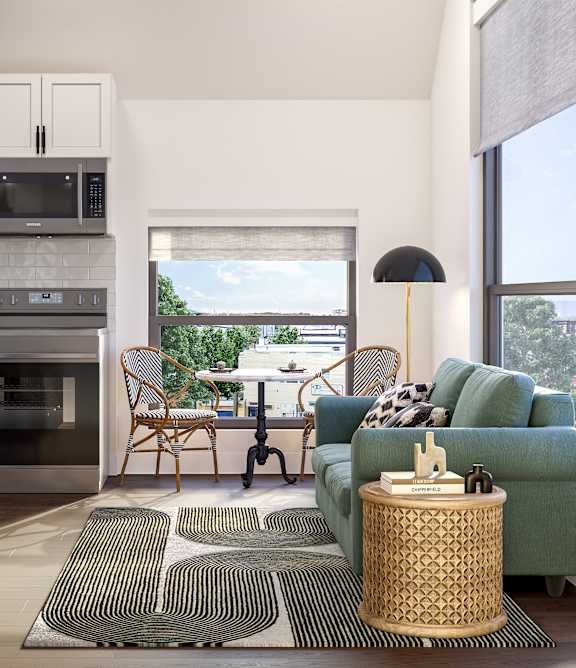 A modern kitchen with a green couch and a dining table.