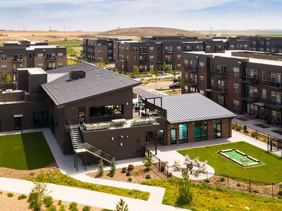 A modern building complex with a green lawn in front.