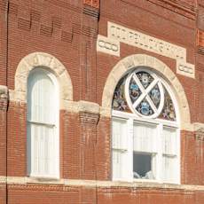 A red brick building with a large arched window on the second floor.