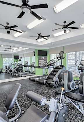A gym with a variety of exercise equipment including treadmills, stationary bikes, and weight machines.
