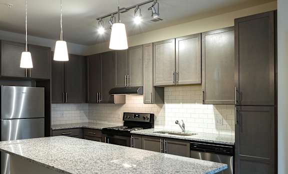 A kitchen with a granite countertop and stainless steel appliances.
