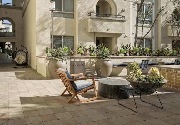 a courtyard with chairs and tables in front of a building