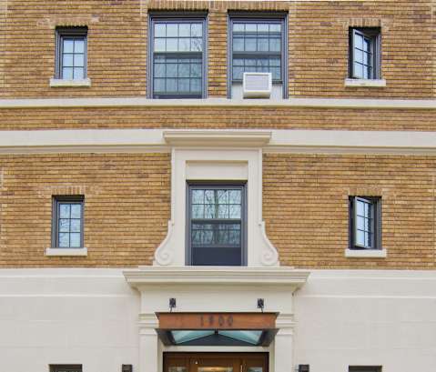 the front of a brick building with a wooden door and benches