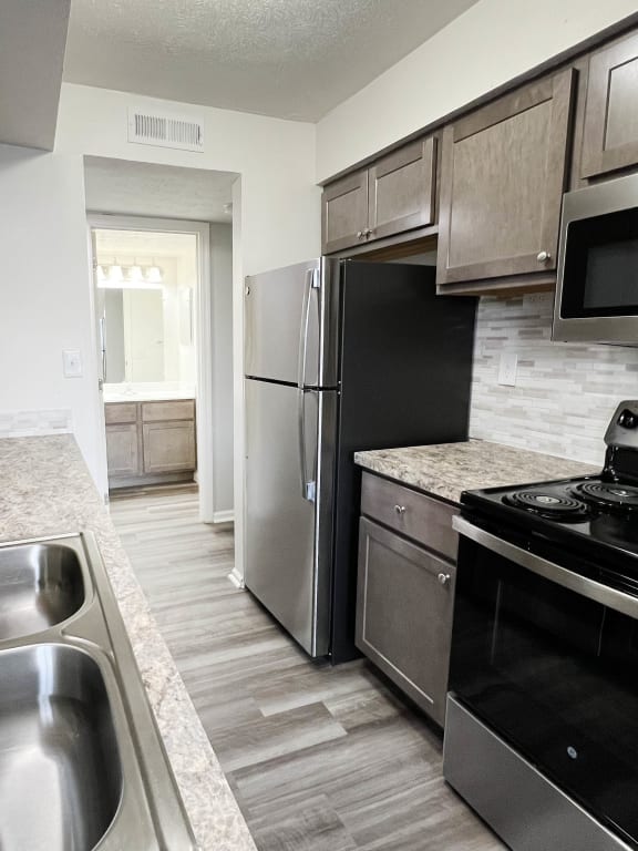 an empty kitchen with stainless steel appliances and marble counter tops at Deercross Apartments, Cincinnati, OH, 45236