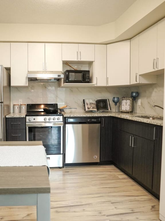 a kitchen with white cabinets and stainless steel appliances and a table