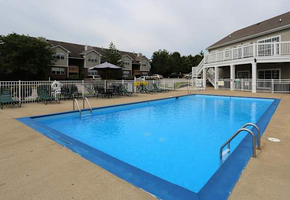 A large blue swimming pool in front of a white building.