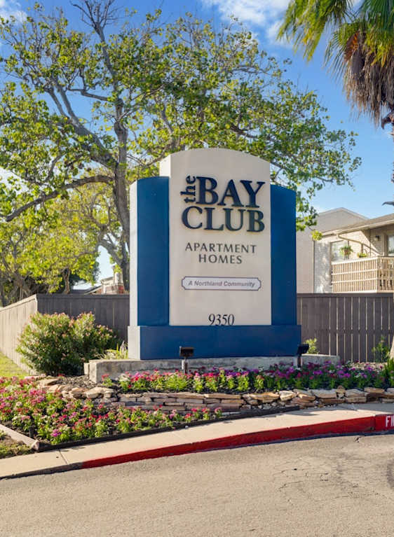 The Bay Club Apartment Homes sign is blue and white.