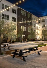 an outdoor courtyard with picnic tables at night