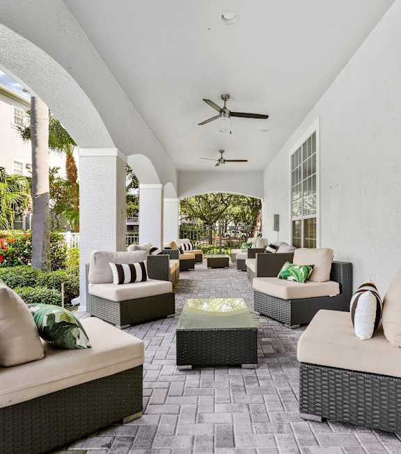 A patio with grey furniture and a ceiling fan.
