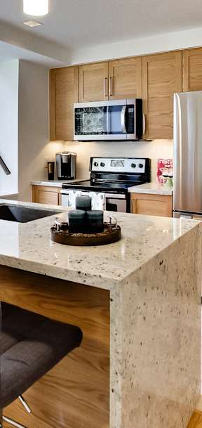 a kitchen with wooden cabinets and a marble counter top and a stainless steel refrigerator