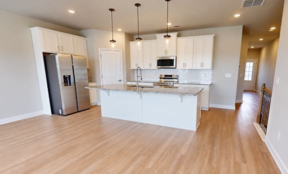 A kitchen with white cabinets and a wooden floor.