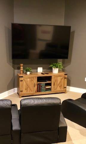 A living room with a large TV, a wooden entertainment center, and black leather chairs.