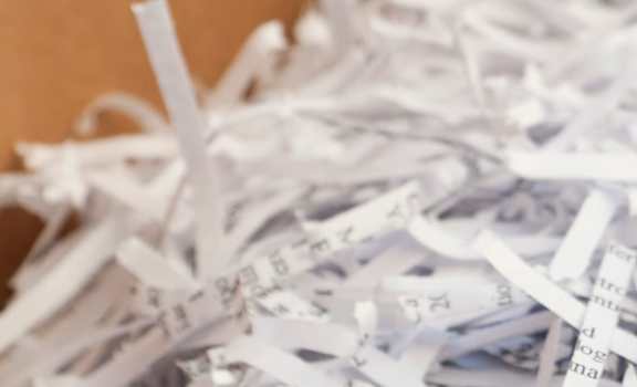 A pile of shredded paper with the text "Stop in anytime with your shredding Residential or Business."