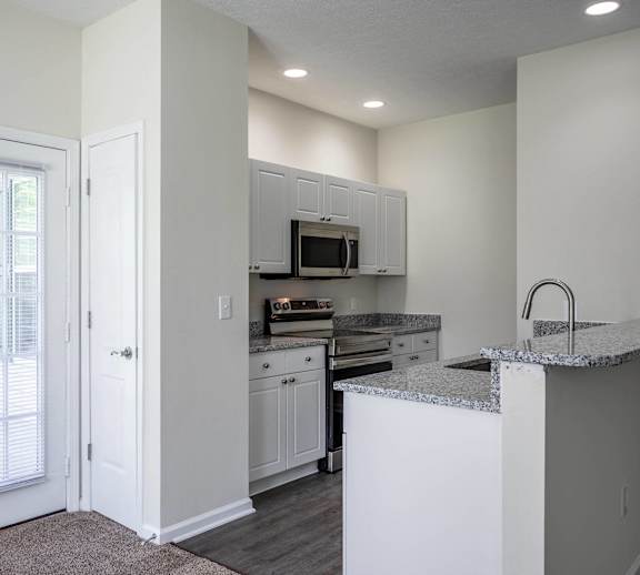 an empty kitchen with white cabinets and a door to a patio