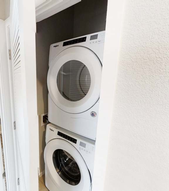 A white door is open to a room with a washing machine in it.