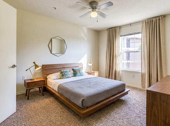 A bedroom with a bed, nightstand, and a ceiling fan.