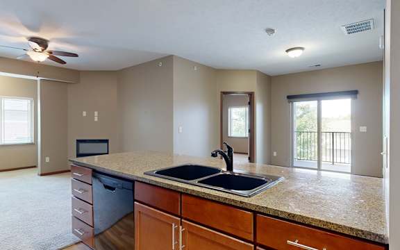 a double bowl stone sink in a kitchen and a living room and dining room adjacent