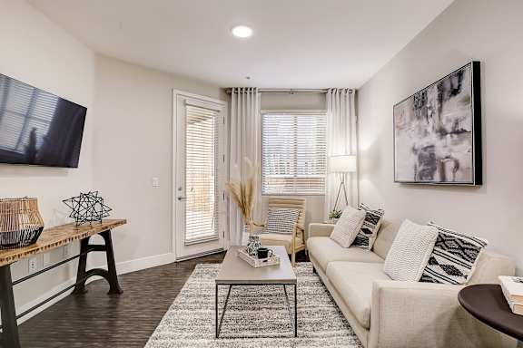 A living room with a beige couch, a coffee table, and a large painting on the wall.