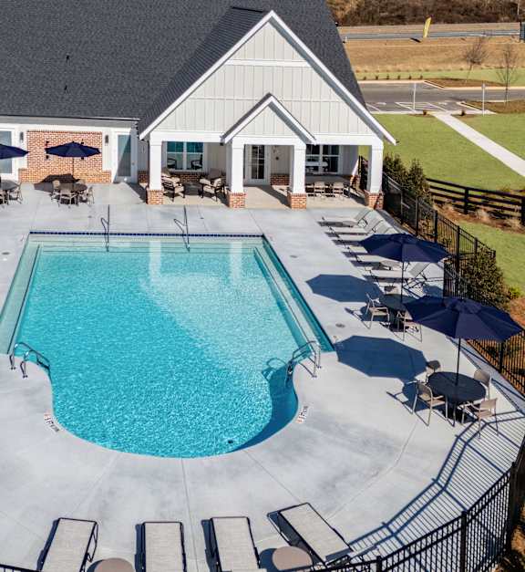 A pool surrounded by a black fence and chairs.
