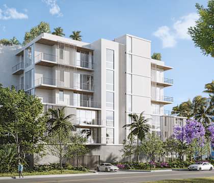 A modern apartment building with balconies and surrounded by greenery and trees.