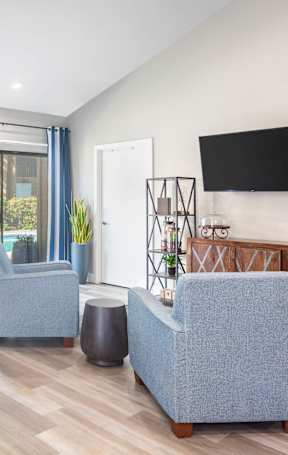 A living room with a grey couch, a brown chair, and a television on the wall.