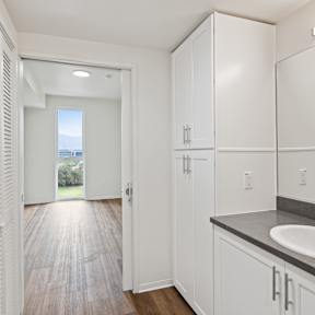 A bathroom with a sink, mirror, and wooden floors.