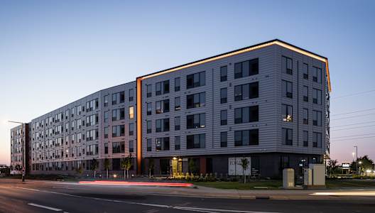 A modern multi-story building with a flat roof and a mix of windows and balconies.