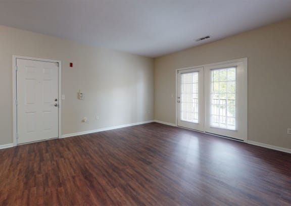 an empty living room with hardwood floors and white walls
