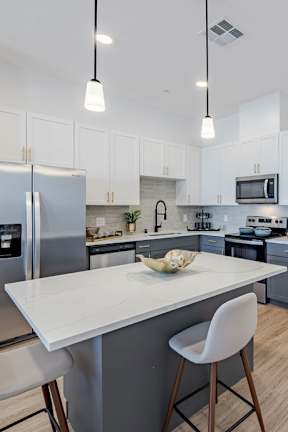 a kitchen with an island and a stainless steel refrigerator