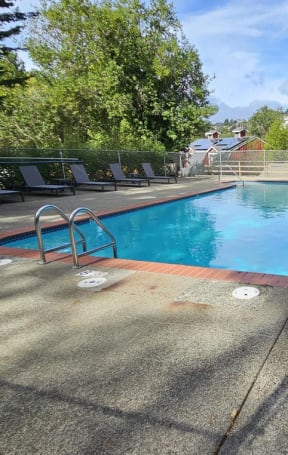 a swimming pool with chairs and a fence around it at Trailhead Apartments at Tam Junction, Mill Valley