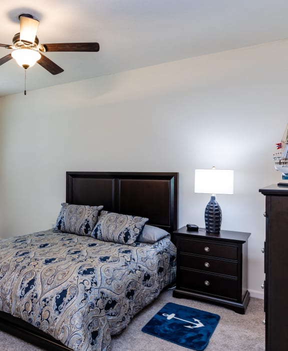 a bedroom with a bed and dressers and a ceiling fan