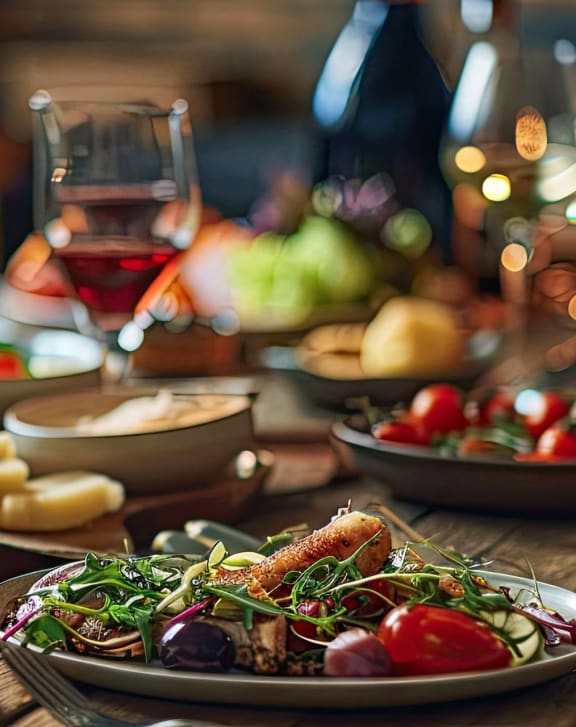 a dinner table with plates of food and glasses of wine