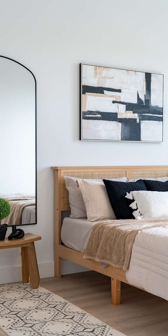 A bedroom with a large bed, a mirror, and a small potted plant.