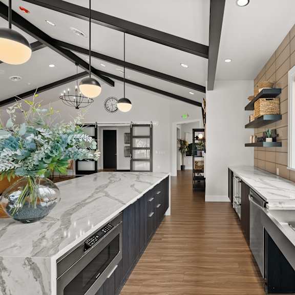 A modern kitchen with a marble countertop and wooden flooring.