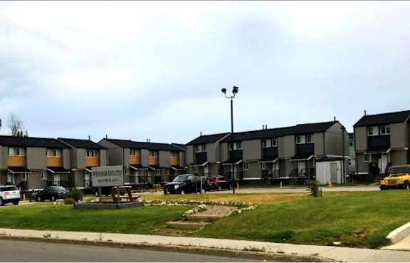 A row of houses with cars parked in front.