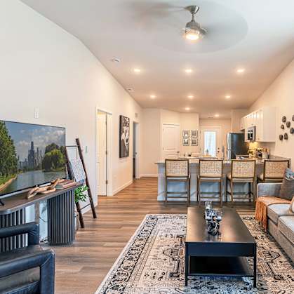 A living room with a grey couch, a black coffee table, and a painting of a landscape on the wall.
