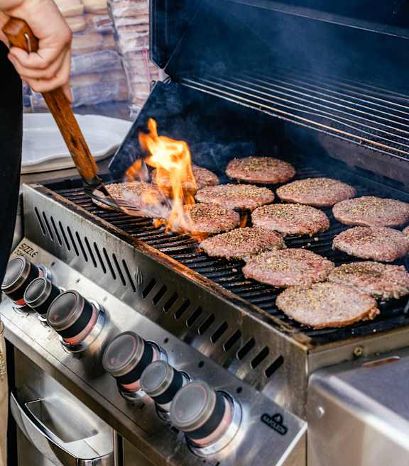 guy cooking burgers on a grill station at Hot Metal Flats apartments, Southside Pittsburgh, PA