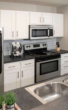 A modern kitchen with a stainless steel refrigerator, microwave, oven, and sink.