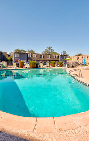 A small pool surrounded by a concrete floor and chairs.