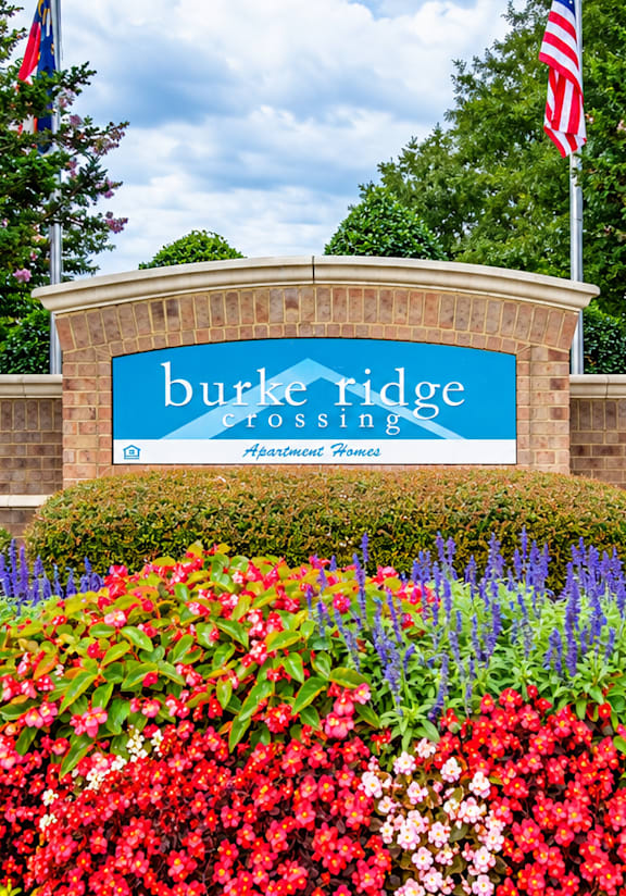 A sign that says Burke Ridge in front of some flowers.