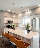 A modern kitchen with a large island and wooden chairs.