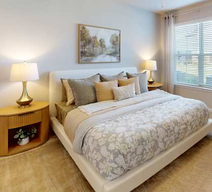 A bedroom with a large bed, a ceiling fan, and a painting on the wall.
