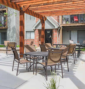 A patio with a table and chairs under a wooden pergola.