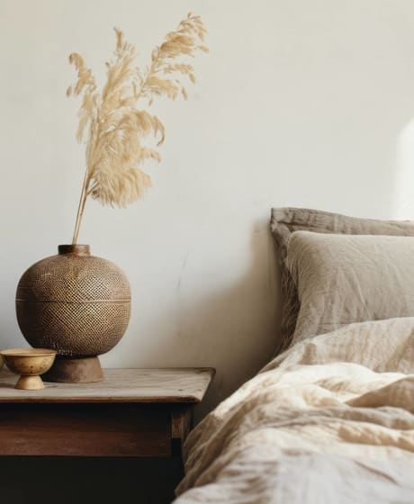 a bed with pillows and a table with a vase and a candle