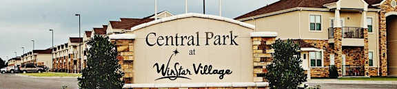 A sign for Central Park at Wister Village is in front of some houses.