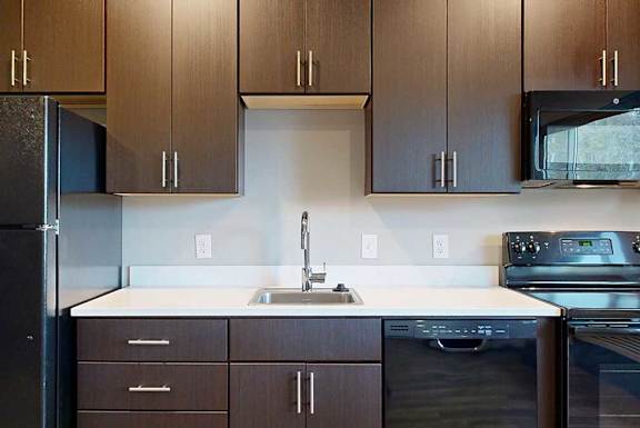 a kitchen with dark brown cabinets and black appliances