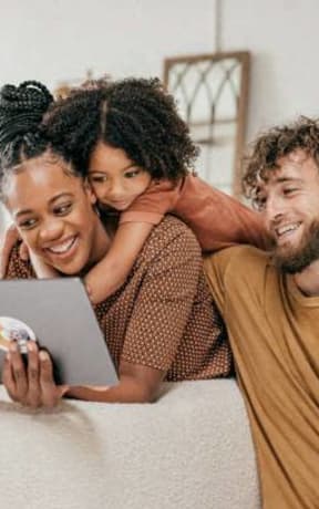 a family lying on a couch, looking into a tablet  at 2000 Oasis  Apartments, Atlanta, GA 30316
